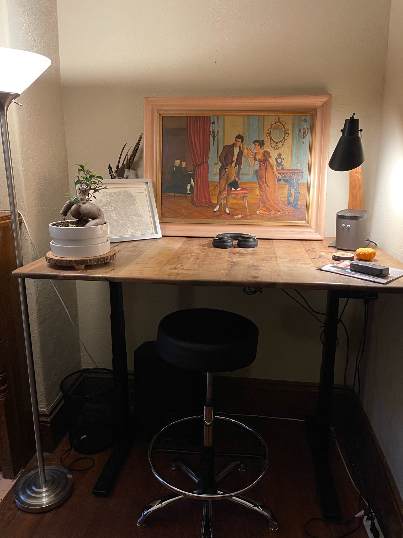 Standing desk workspace with bonsai and vintage painting