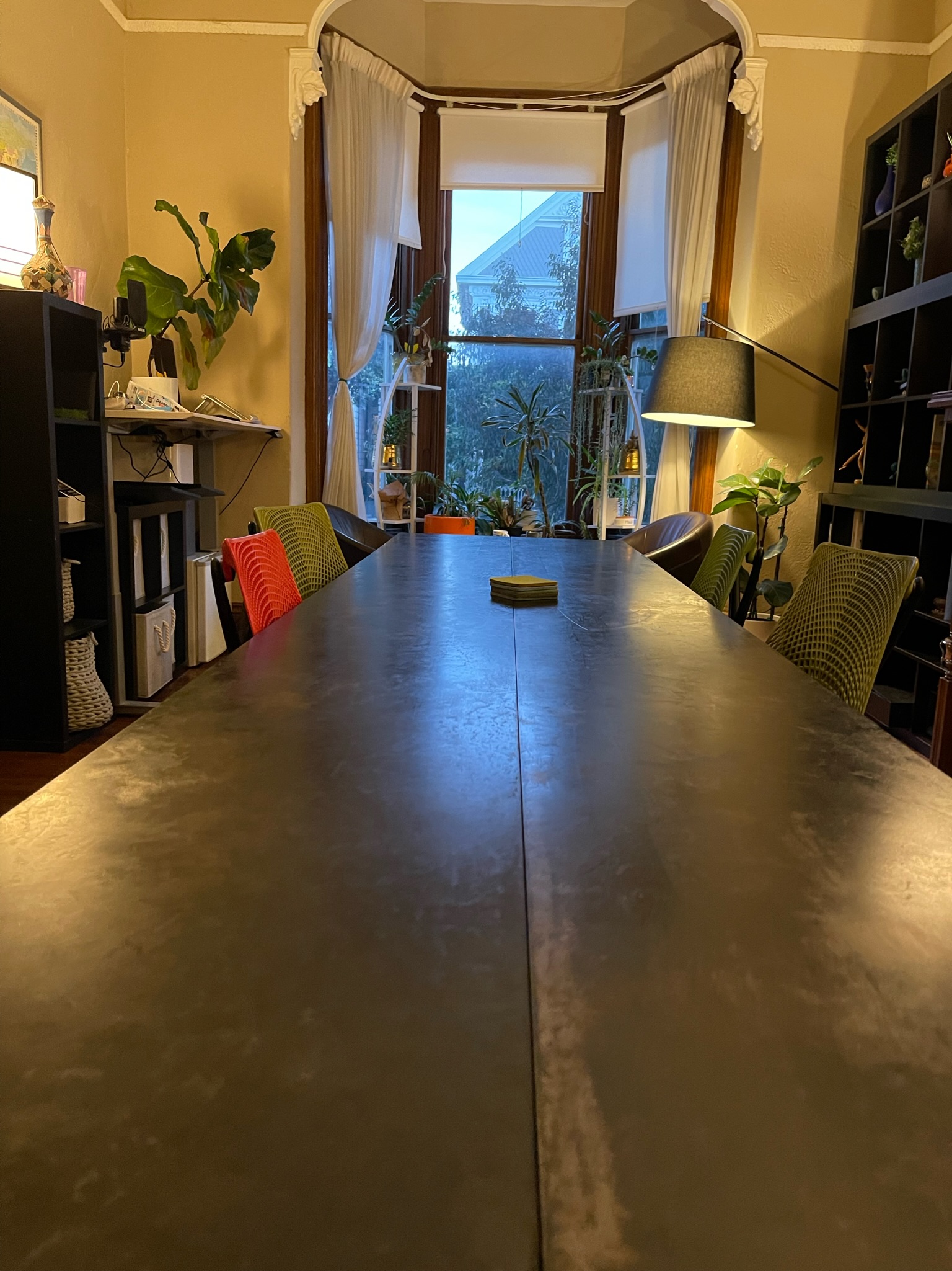 Long coworking table with colorful chairs and bay window